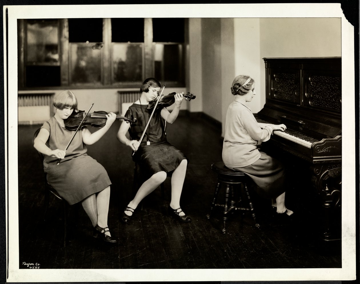 Gruppe på tre unge blinde kvinner, en ved pianoet, to spiller fioliner, ved New York Association for the Blind, 111 East 59th Street, New York, 1926 (sølv gelatintrykk) av Byron Company