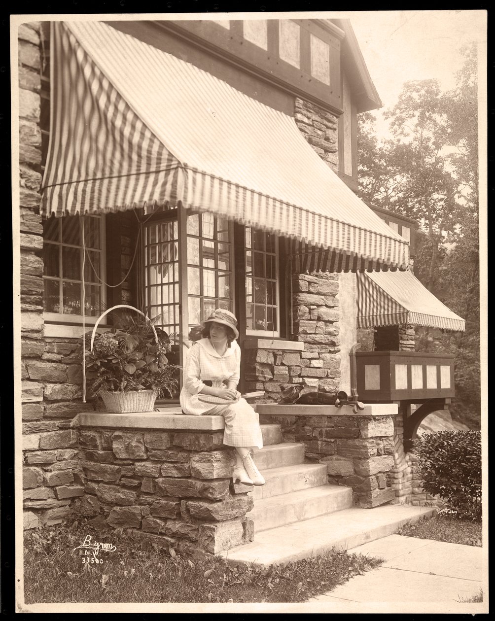 En kvinne som satt ved inngangen til et hus, 1915 (sølv gelatintrykk) av Byron Company