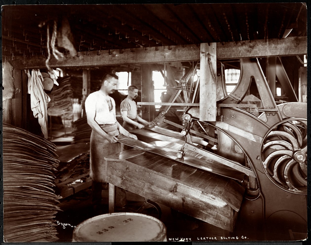 Interiørbilde av to menn som arbeider med lær og tungt utstyr ved New York Leather Belting Co., New York, 1905 (sølv gelatintrykk) av Byron Company