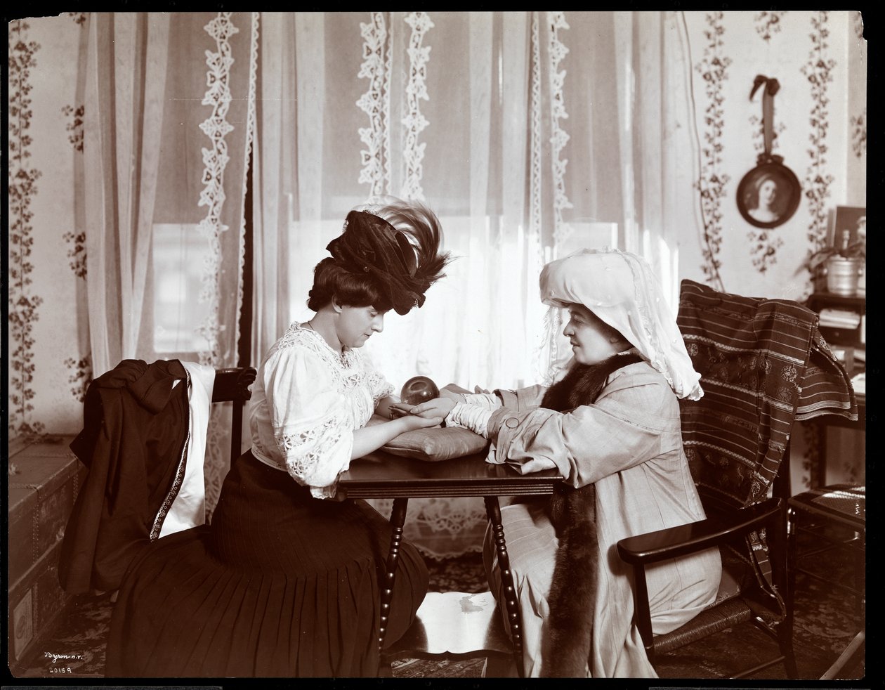 Mrs. Leslie Carter sittende med en kvinne som leser en krystallkule, 1904 (sølv gelatintrykk) av Byron Company