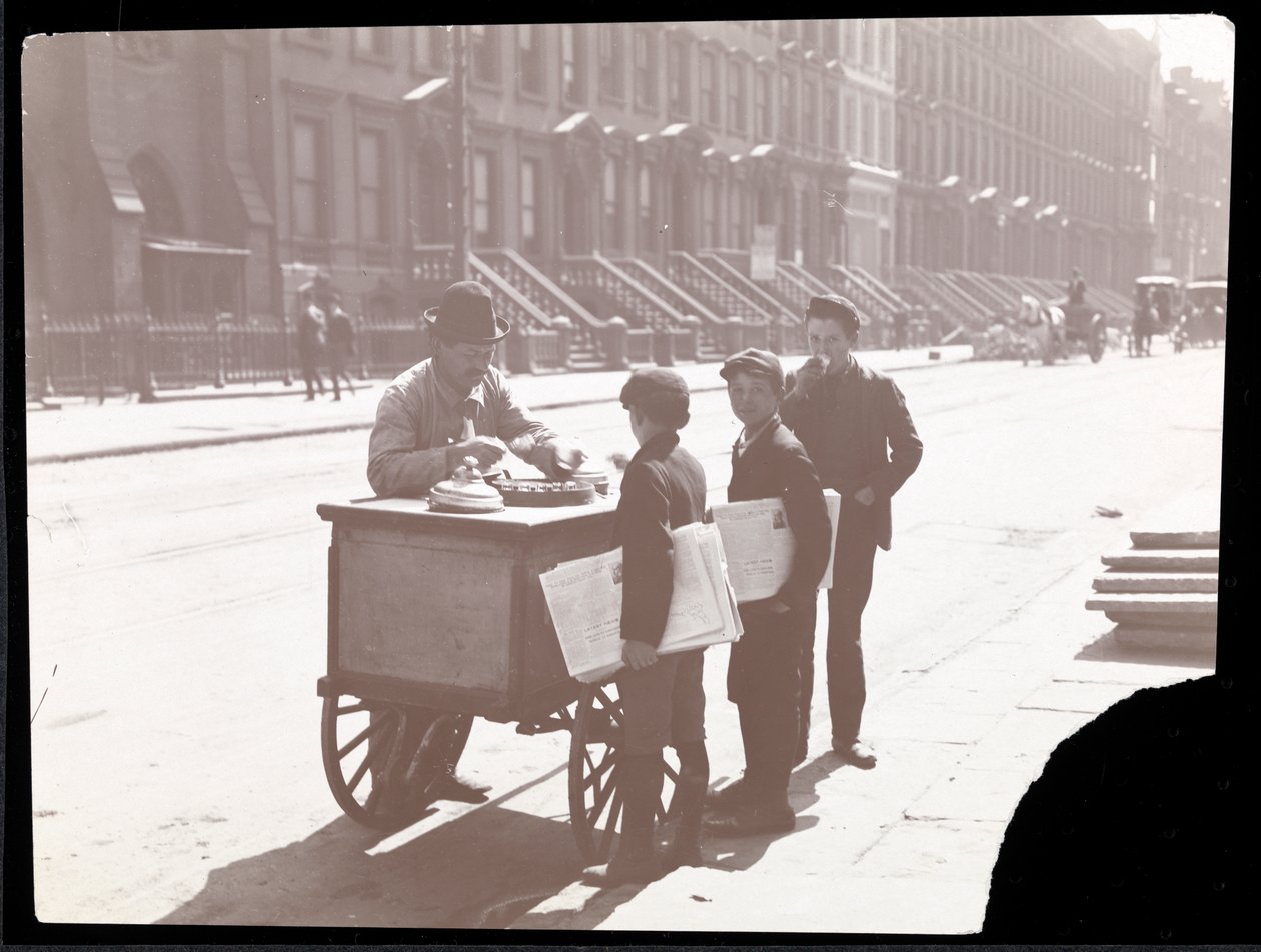 Utsikt over en iskremhandler på gaten, med tre avisgutter som kjøper is, New York, ca. 1901 (sølv gelatintrykk) av Byron Company