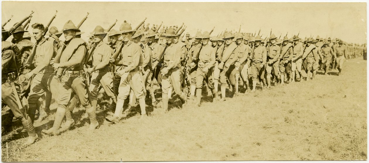 Horisontalt sepia -fotografi som viser rader med uniformerte soldater som marsjerer gjennom et gressfelt i formasjon mens de bærer rifler av Carl Michel