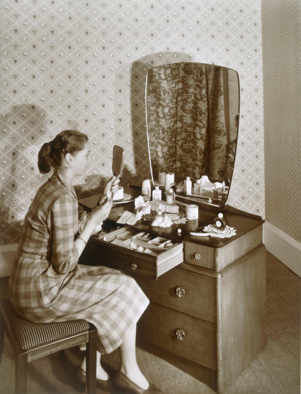 Kvinne ved sminkebordet hennes, c1955. av English Photographer