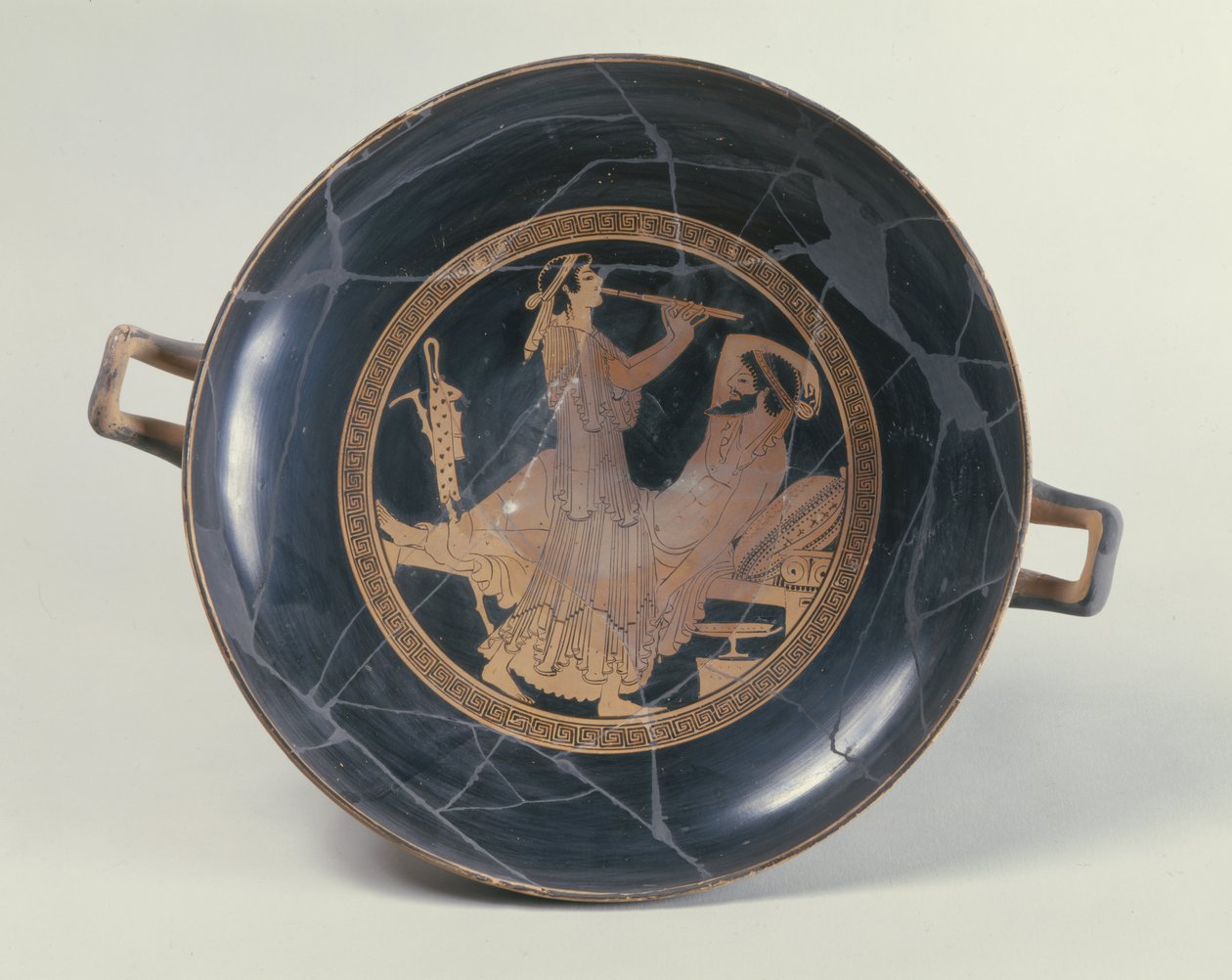 Loftskopp med rød figur som viser en kvinne som spiller en dobbelfløyte (keramikk) av Greek