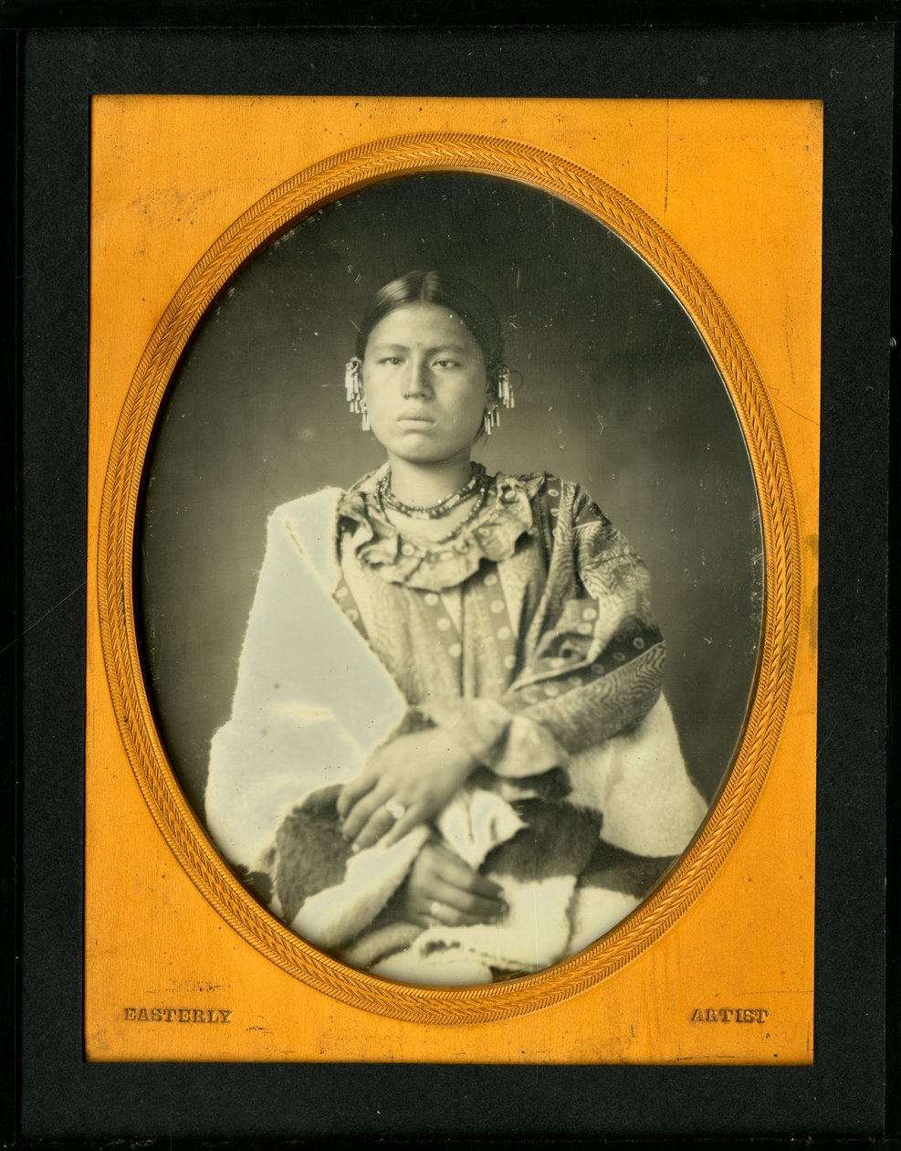 Portrett av kona til Mahee (Knife), Iowa. (Kun-zan-ya). Kona til Mahee bærer et tykt teppe rundt henne og smykker med perler. av Thomas M. Easterly