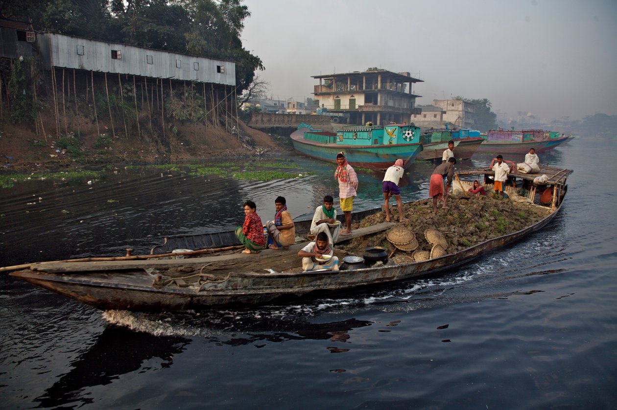 En båt som frakter jord, brukt til å fylle opp lavt land, gjennom Shitalakhya-elven, nær Tongi-broen, i utkanten av byen Dhaka. Bangladesh. 19. februar 2007. av Unbekannt Unbekannt